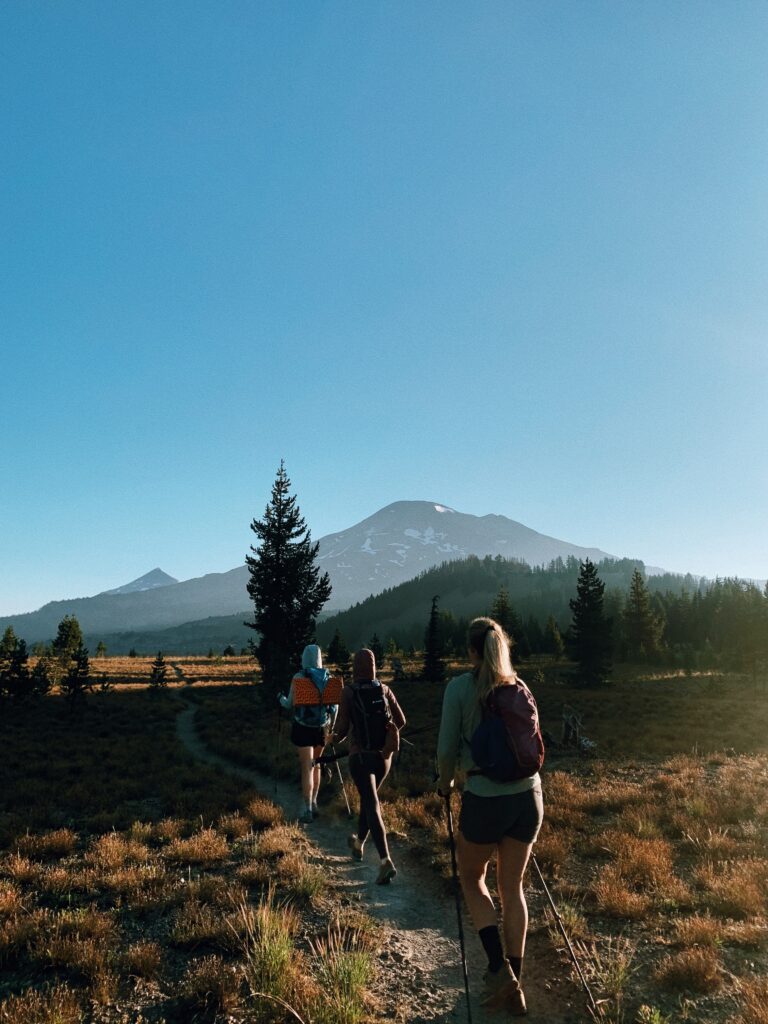 Three woman hiking on a trail with blue sky